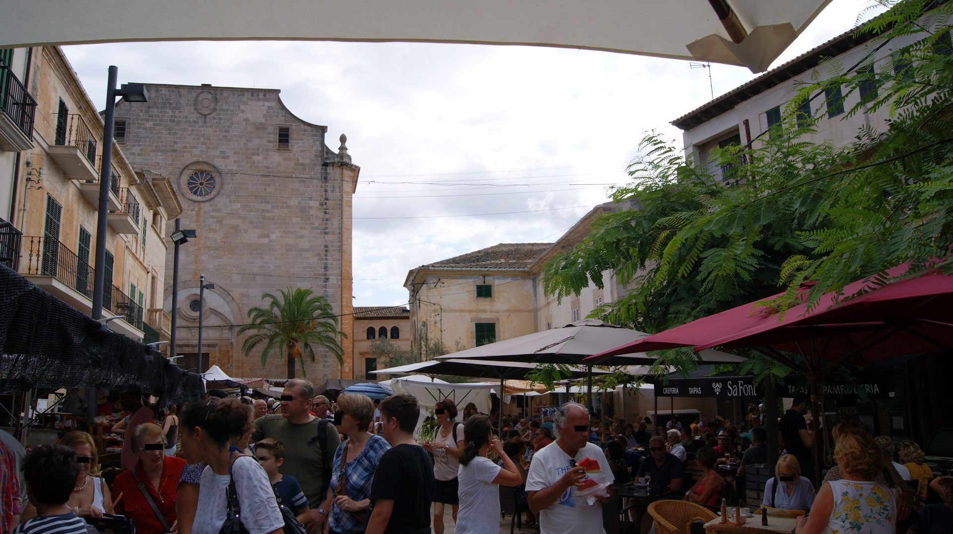 Marktbetrieb auf der Plaça Major in Santanyí vor der charakteristischen Sandsteinkirche